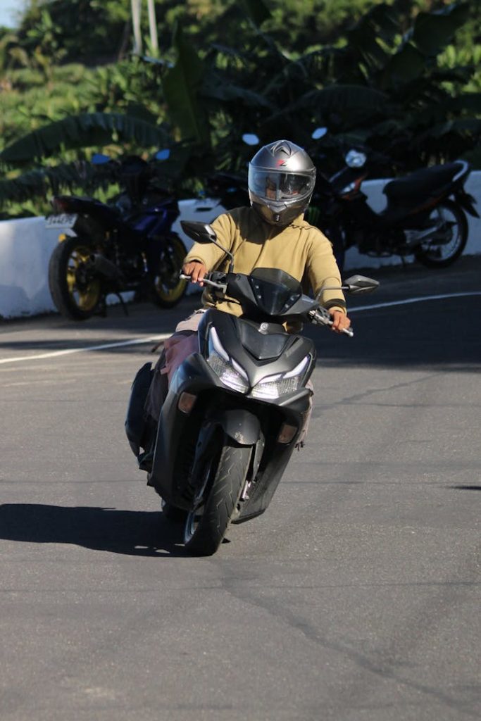 Adult wearing helmet riding scooter on sunny day, showcasing safety and travel.